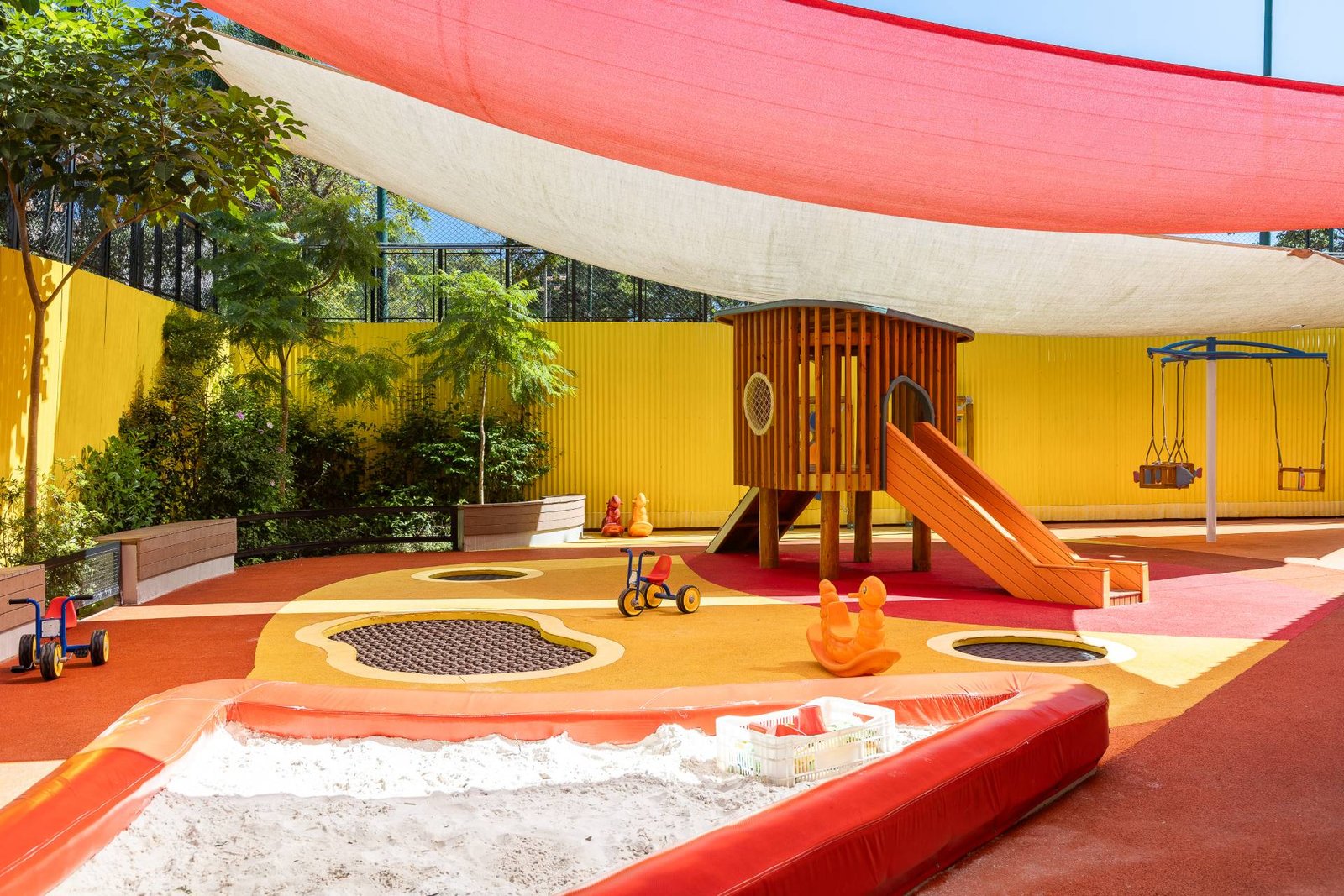 Parque infantil com cobertura de sombreamento colorida, casa de madeira e piso emborrachado