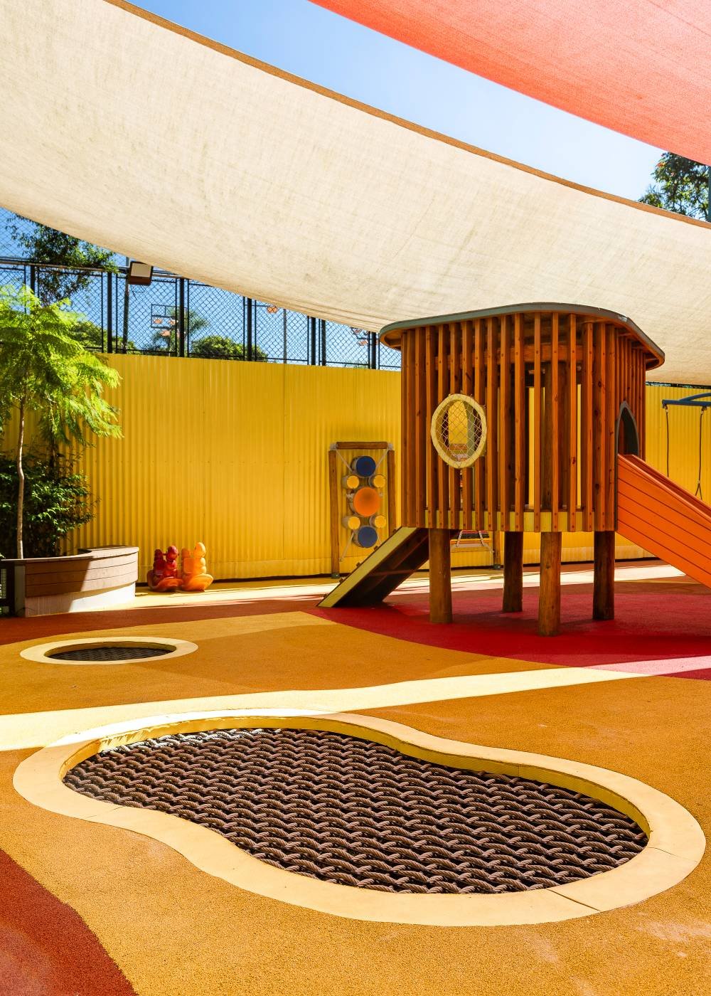 Setor Primavera coberto, com casa de madeira, piso laranja e trampolins ao nível do chão