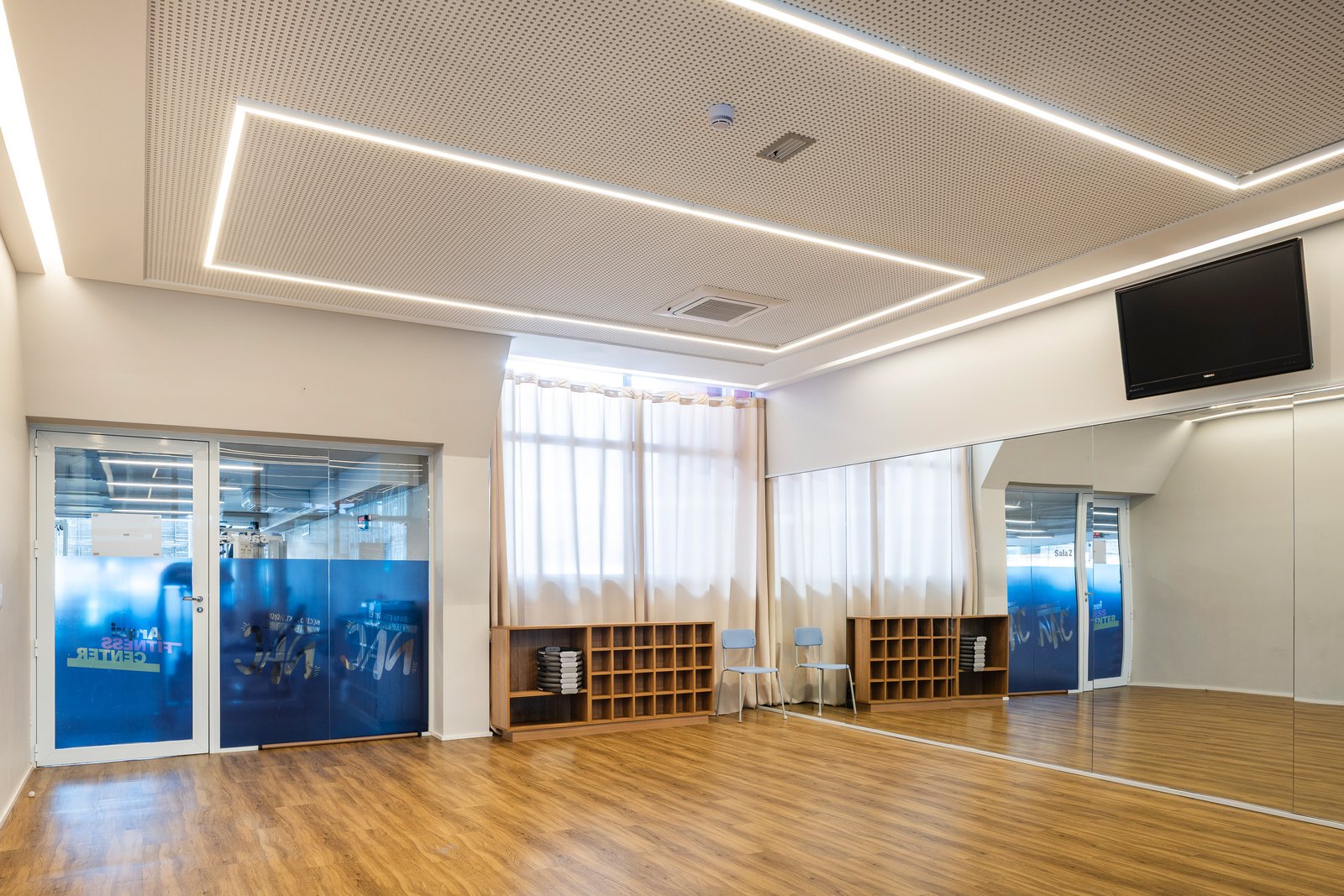 Sala de dança entregue, com piso de madeira, espelho e vidros jateados com a marca NAC