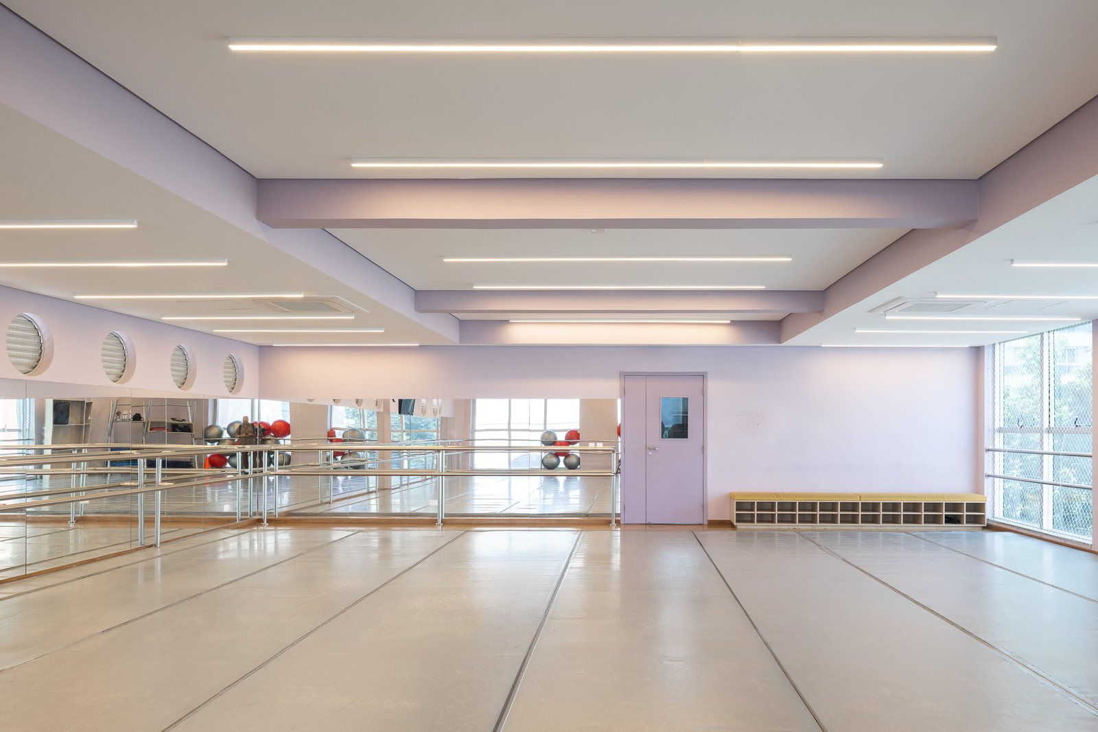 Sala de dança em tons de lilás, com barra, espelhos e forro renovado