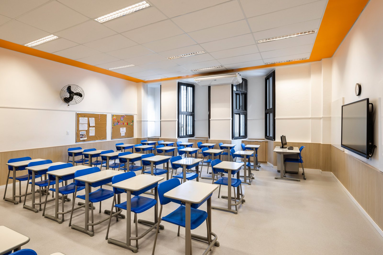 Corredor com forro laranja e murais de trabalhos dos alunos
