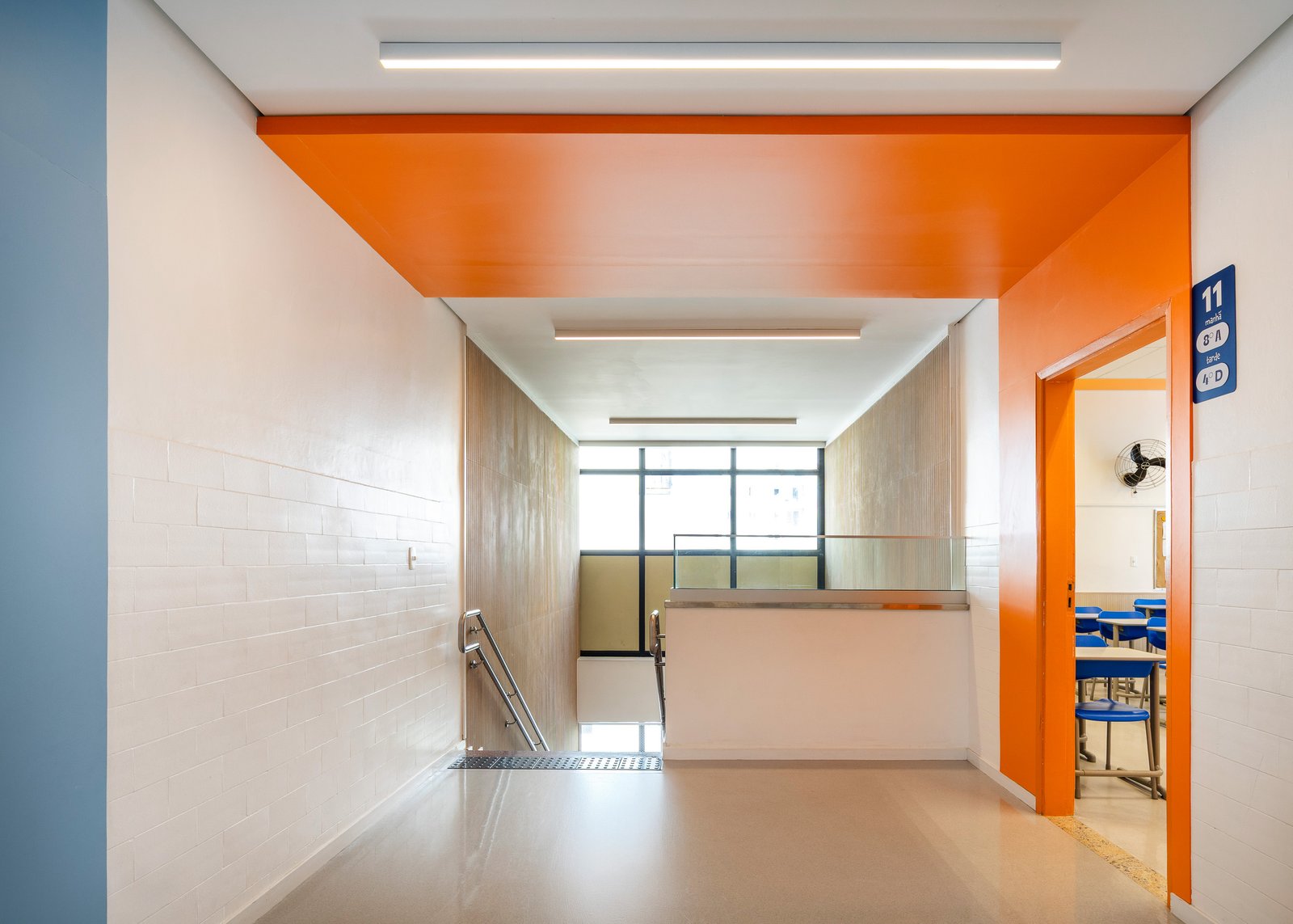 Sala com friso verde no teto, mural de cortiça e almofadas coloridas no piso