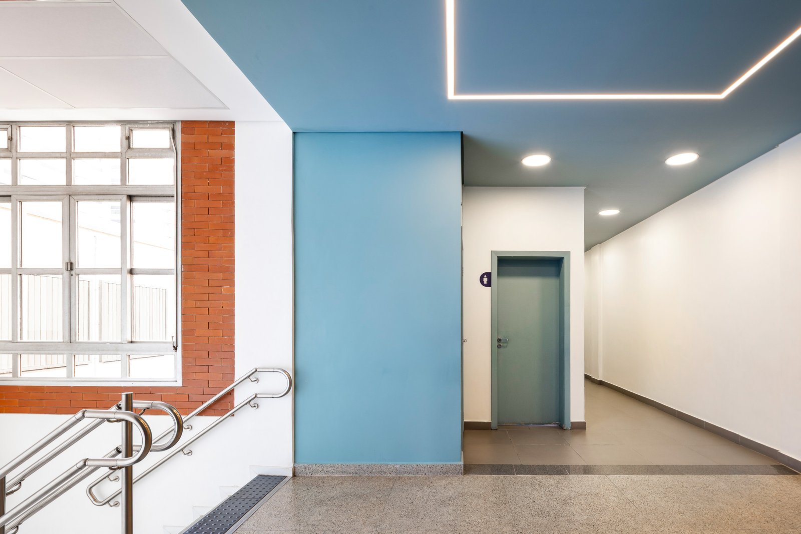 Sala com porta verde, lousa branca, TV e área de estar informal