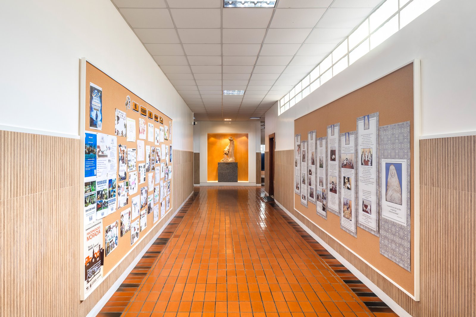 Sala de aula com carteiras azuis, mural de boas-vindas e janelas amplas
