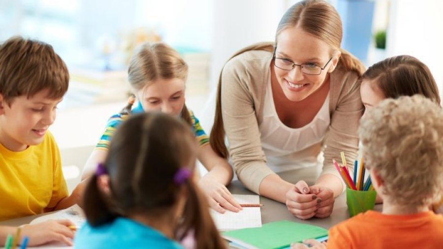 Portrait of diligent schoolkids and their teacher talking at lesson